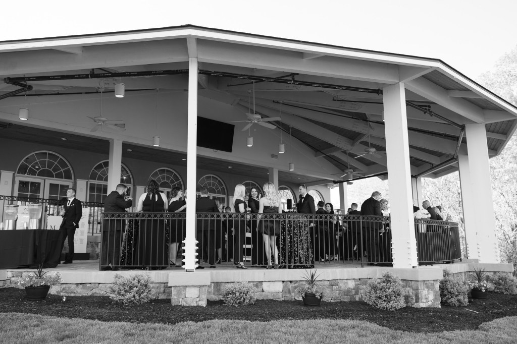 Black and white photo of wedding guests relaxing on the patio